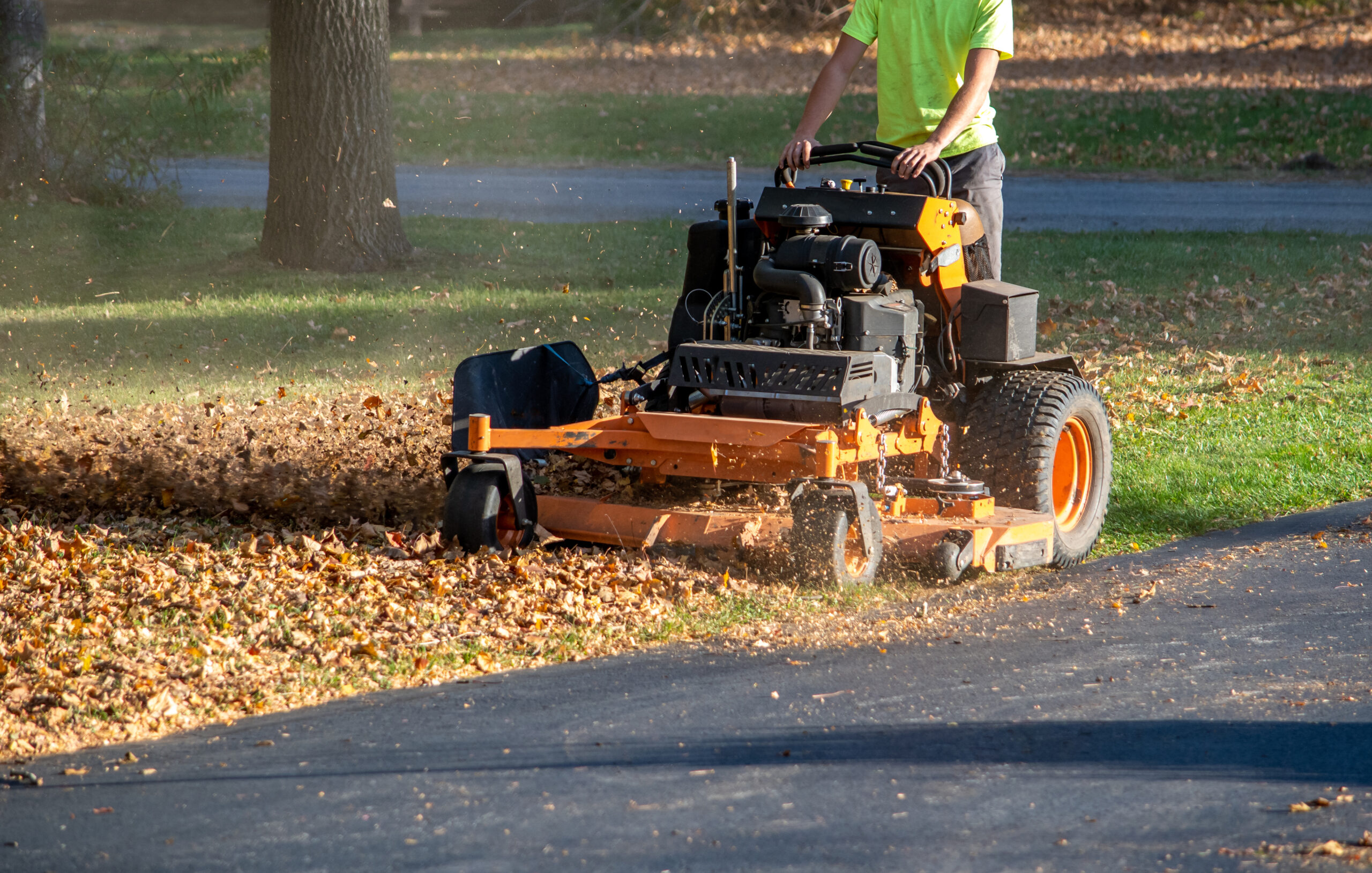 Worker on a Standing mower and leaf mulcher, doing fall clean up